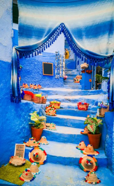 Chefchaouen, Morocco. Blue staircase and wall decorated with colourful flowerpots, Chefchaouen medina, North Africa travel destination.
